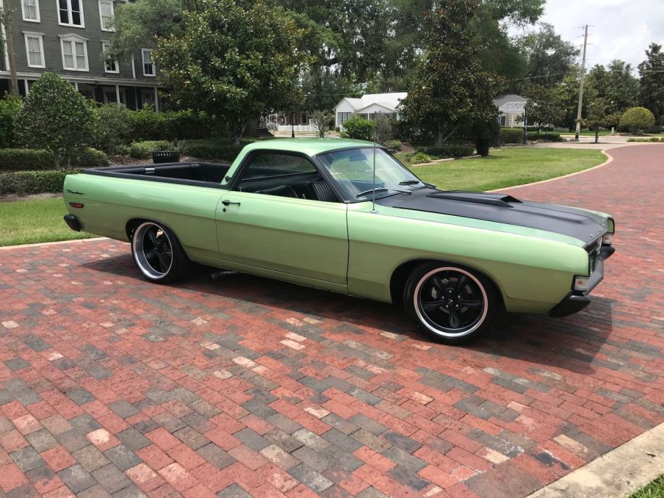 Light green 1970 Ford Ranchero with black hood and custom wheels parked on brick driveway