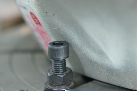 1979 Ford Bronco - A close-up view of a bolt and nut assembly against a metallic background, with partial red text visible.