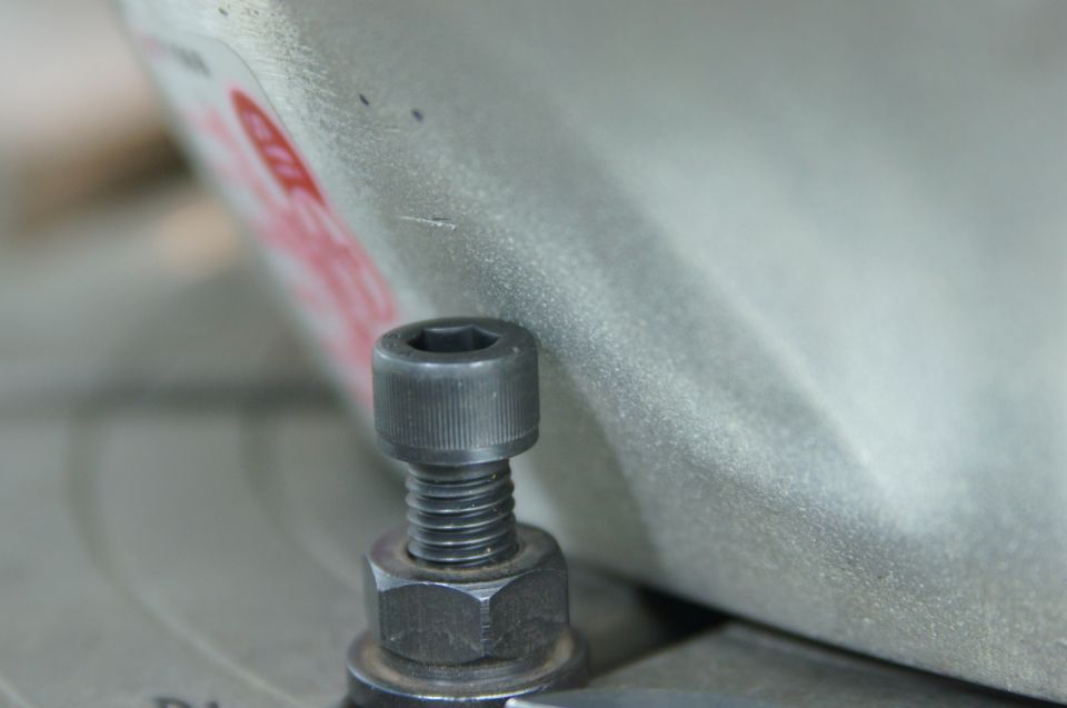 Close-up of a hex bolt and nut on a textured metal surface with red lettering