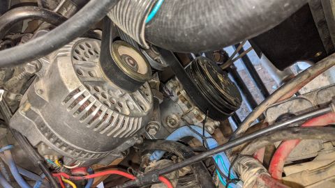 1995 Ford Bronco - Close-up view of an engine's alternator and serpentine belt system.