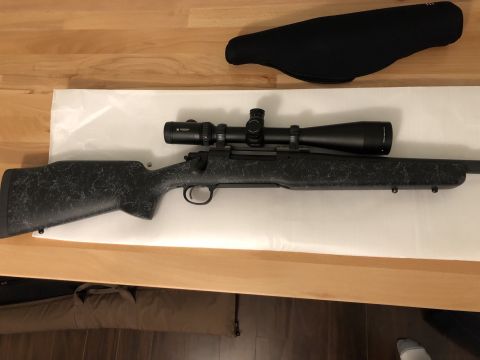 1995 Mercury Grand Marquis - A rifle with a scope and a black stock is displayed on a wooden surface.