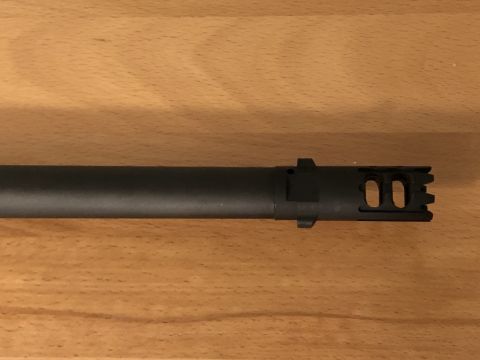 1995 Mercury Grand Marquis - A black muzzle brake with dual oval ports and serrated teeth is shown against a wooden background.