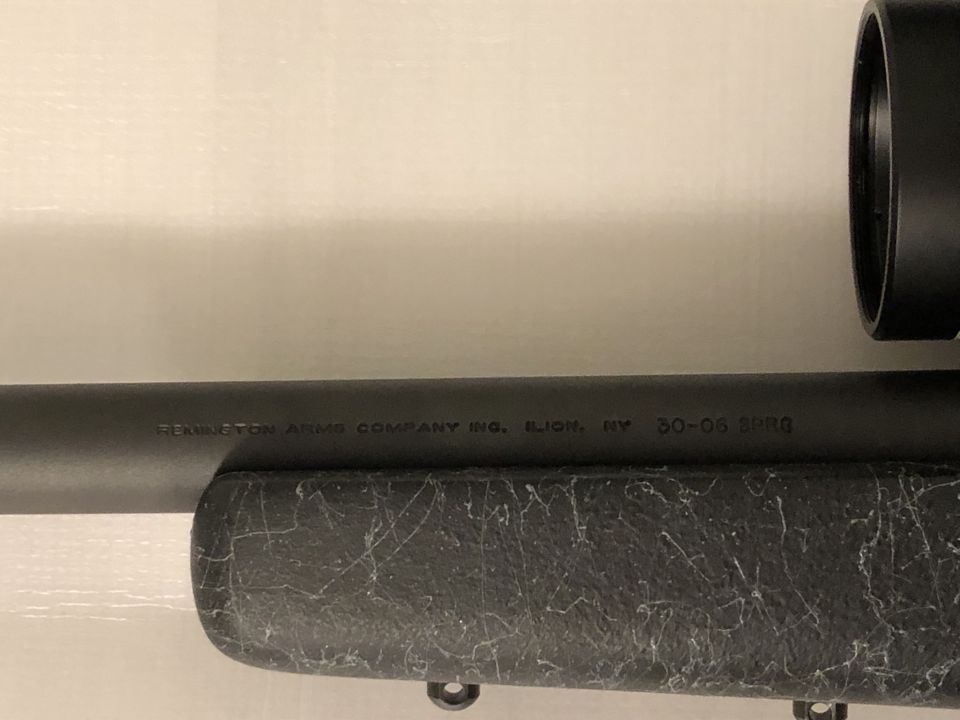 Rifle barrel with text: REMINGTON ARMS COMPANY INC. ILION, NY 30-06 SPRG. Scope visible