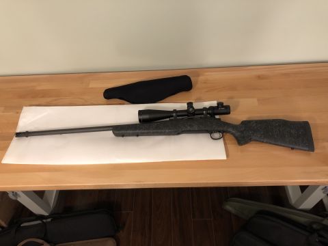 1995 Mercury Grand Marquis - A rifle with a scope and a gun sock are laid out on a table.