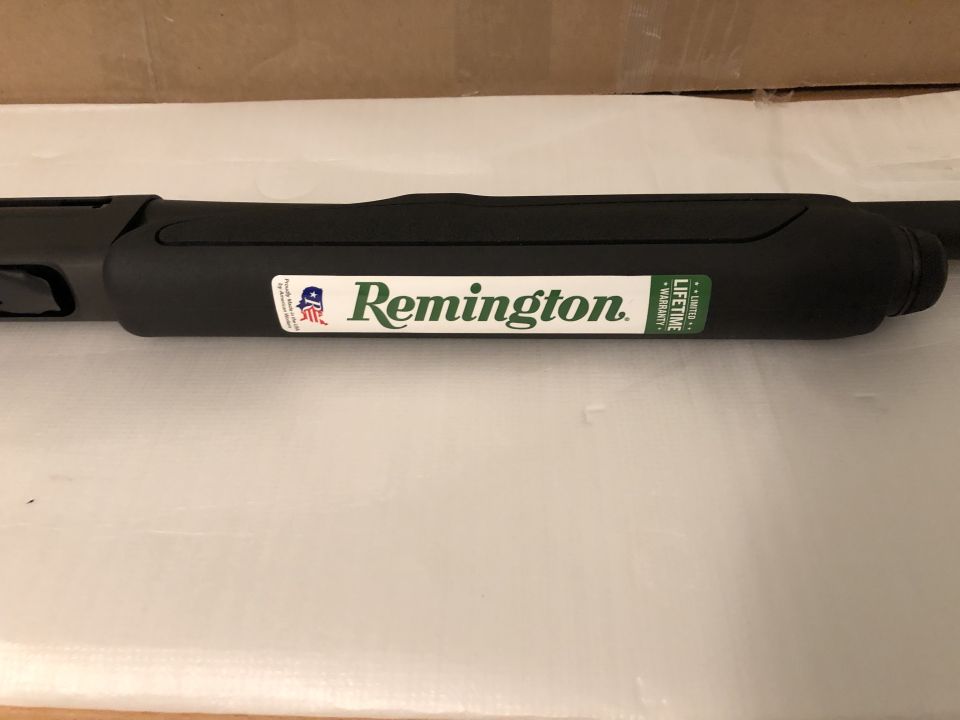 Black Remington shotgun barrel with a white and green logo sticker and a green warranty sticker