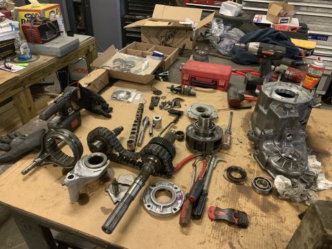 2000 Jeep Cherokee - Various parts of a transfer case are spread across a workbench, suggesting a repair or rebuild.