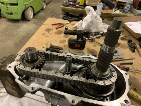 2000 Jeep Cherokee - Disassembled transfer case showing internal gears and drive chain, with tools nearby.