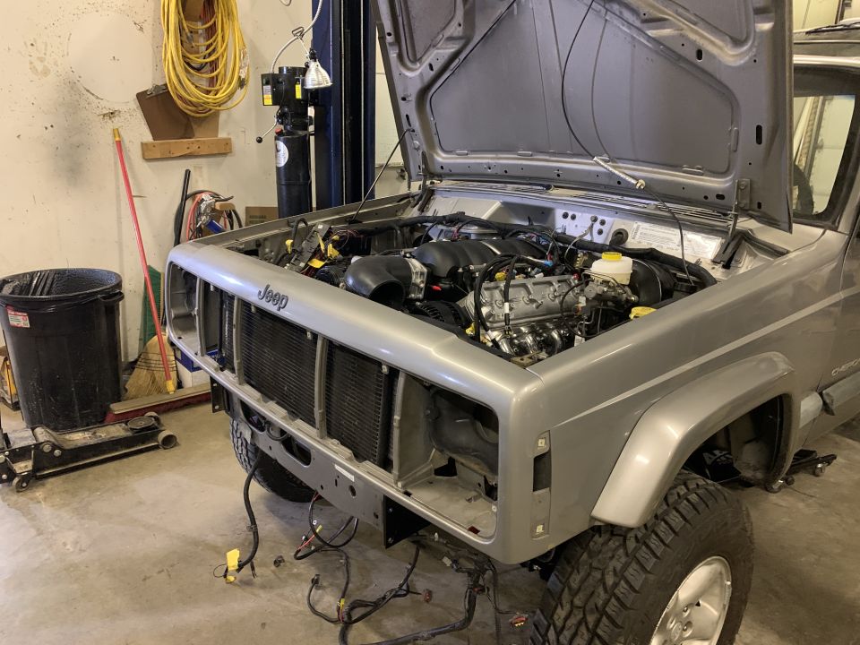 Silver Jeep Cherokee front view, hood open, engine exposed, in garage