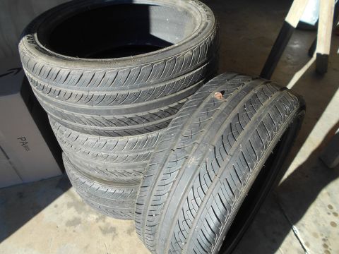 1992 Ford Bronco - A stack of tires sits on a concrete surface, with one tire showing a nail embedded in its tread.