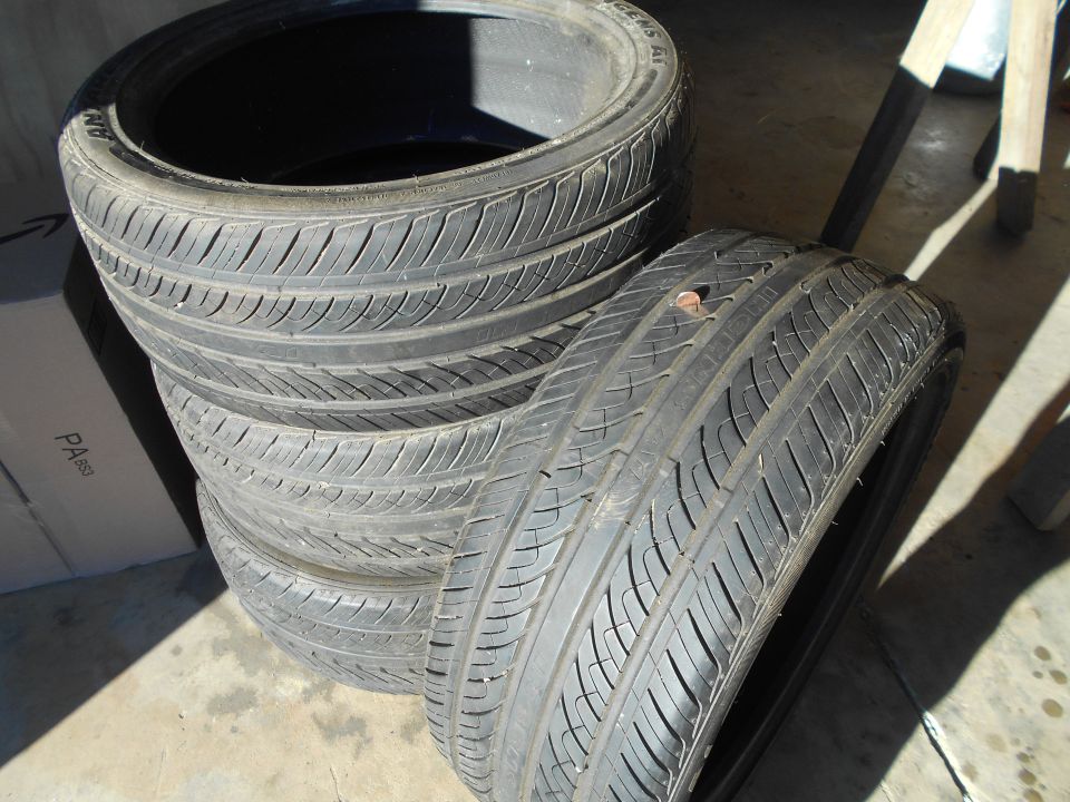 stack of four tires, one with a nail in it