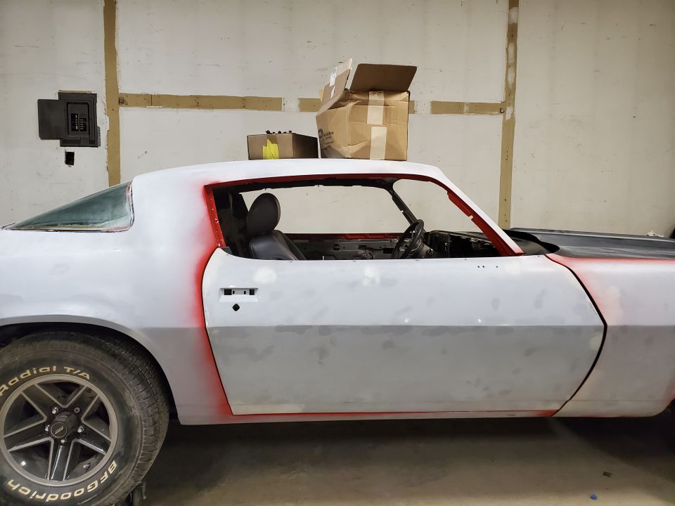 Side view of a white and red primer classic car with black interior and BFGoodrich tires