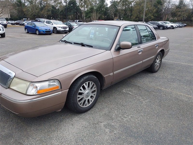 Tan Mercury Grand Marquis sedan parked on asphalt, front passenger side visible