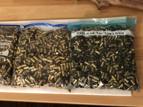 1995 Mercury Grand Marquis - Several bags of brass casings, likely from ammunition, are spread out on a wooden surface.