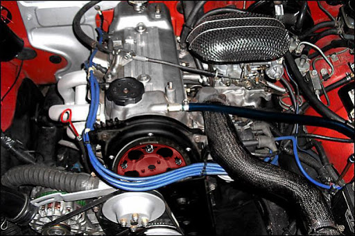 Engine bay with red accents, black air filter, and blue spark plug wires