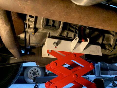 1996 Ford Bronco - A vehicle's transmission is supported by a red scissor jack during maintenance.