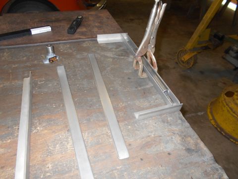 1992 Ford Bronco - Metal parts are being prepared for assembly on a workbench, with a floor jack visible in the background.