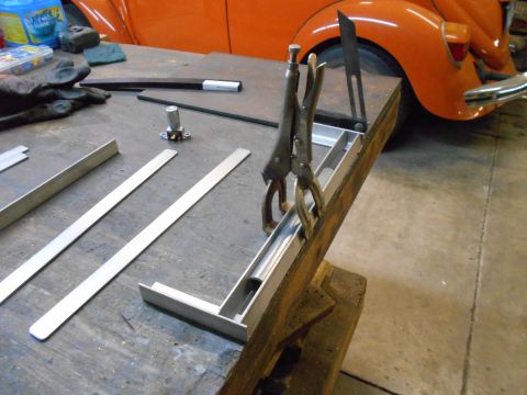 1992 Ford Bronco - An orange car's rear fender and bumper are visible in the background of a workbench scene.