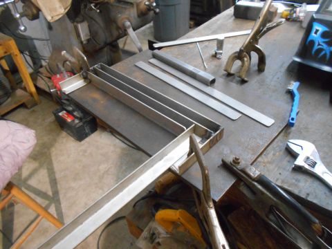 1992 Ford Bronco - A workbench displays a metal fabrication project aluminum channels, welding equipment, and various tools.