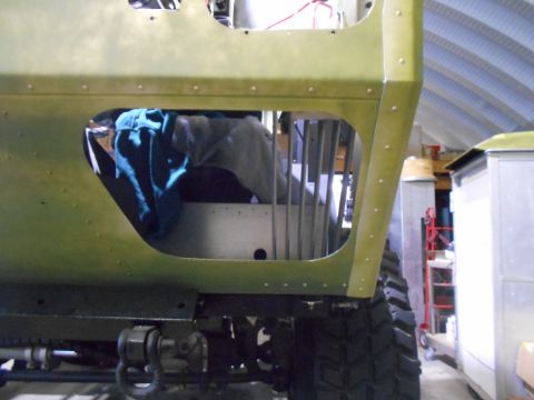 1992 Ford Bronco - The side panel of a vehicle is open, revealing internal structure and some stored items within a workshop setting.