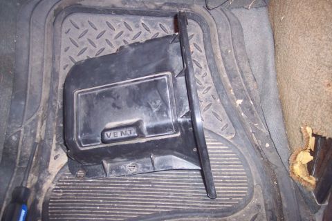 1978 Ford Bronco - Close-up of a vehicle's interior showing a heater vent cover on the floor mat.