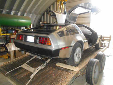 1992 Ford Bronco - A DeLorean DMC-12 is being loaded onto a trailer inside a workshop.