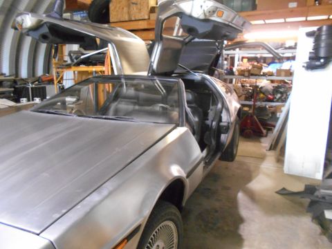 1992 Ford Bronco - A DeLorean DMC-12 is shown with its distinctive gullwing doors open in a workshop.