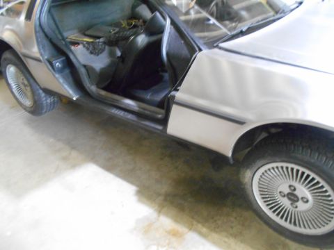 1992 Ford Bronco - Side view of a DeLorean DMC-12, door ajar, revealing the interior and front wheel.