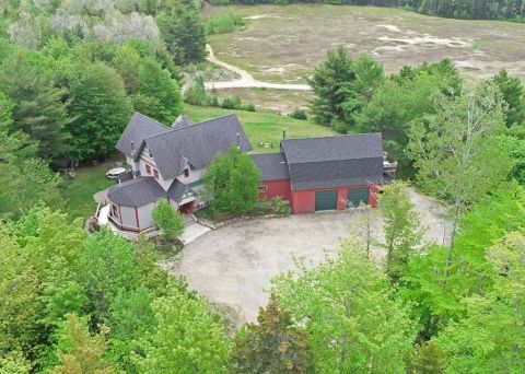 1992 Jeep Wrangler - An aerial perspective captures a spacious residence and its adjacent red garage, enveloped by lush green foliage.