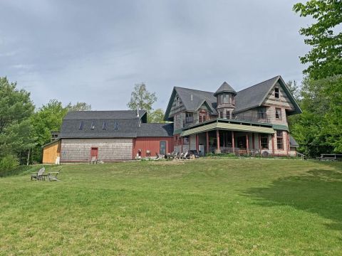 1992 Jeep Wrangler - A large house and attached barn are situated on a grassy hill under a partly cloudy sky.