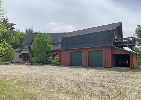 1992 Jeep Wrangler - A large house is attached to a red garage with two bays and an open carport where a vehicle is visible.