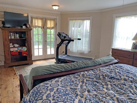 1992 Jeep Wrangler - A bedroom scene a treadmill, a television on a wooden bookshelf, and double doors opening to an outdoor view.