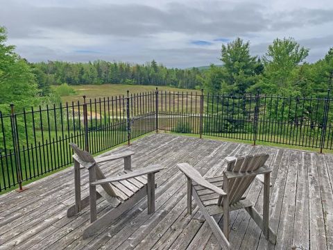 1992 Jeep Wrangler - A tranquil outdoor scene with Adirondack chairs on a wooden deck, offering a view of a field and distant trees.