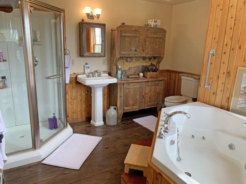 1992 Jeep Wrangler - This bathroom features a shower stall, a pedestal sink, rustic wooden cabinetry, and a large jacuzzi tub.