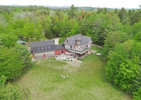 1992 Jeep Wrangler - A large house with a distinctive tower sits on a hill, surrounded by lush green trees and a well-maintained lawn.