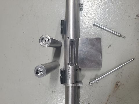 1996 Ford Bronco - A disassembled gun bolt assembly is laid out on a gray surface, showing various metal components and a visible serial number.