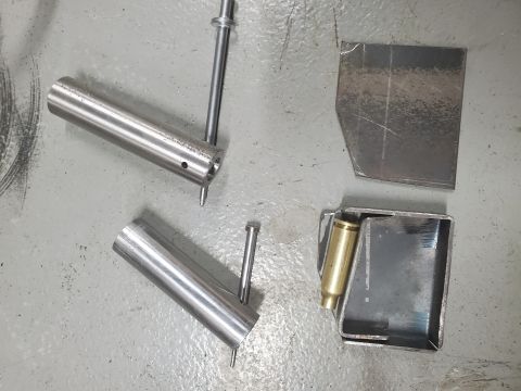 1996 Ford Bronco - Various metal parts and a brass casing are laid out on a concrete surface.