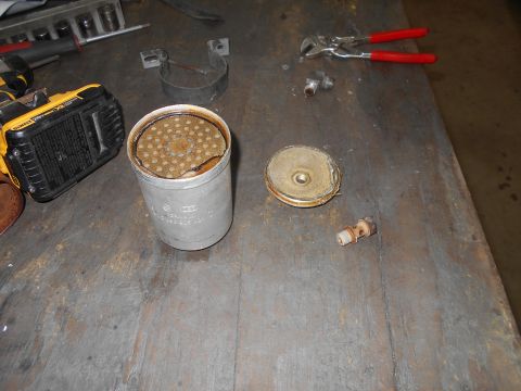 1992 Ford Bronco - Oil filter housing and related parts are laid out on a workbench, alongside a power tool and pliers.