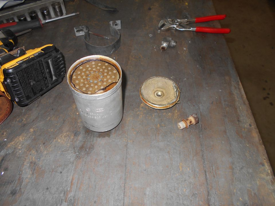 Disassembled oil filter housing with tools on a workbench