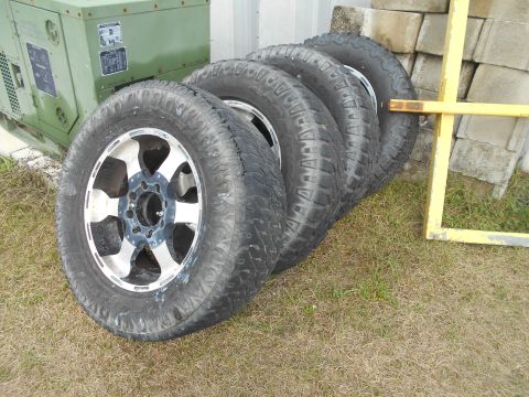 1992 Ford Bronco - Four tires and rims are displayed outdoors, with a generator and building materials in the background.