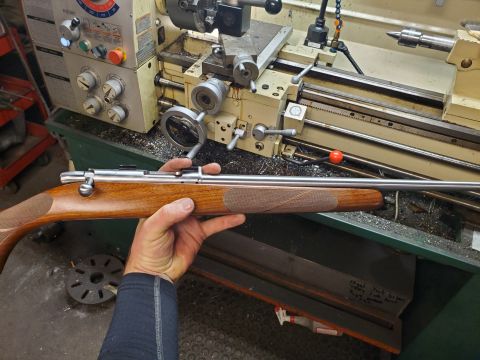 1996 Ford Bronco - A person holds a rifle with a wooden stock in front of a metalworking lathe.