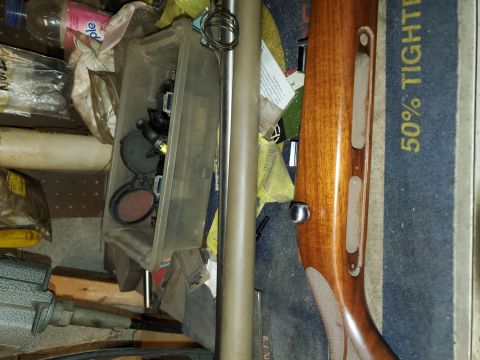 1996 Ford Bronco - Various hunting equipment, including a rifle stock and scope, are stored together in a disorganized space.