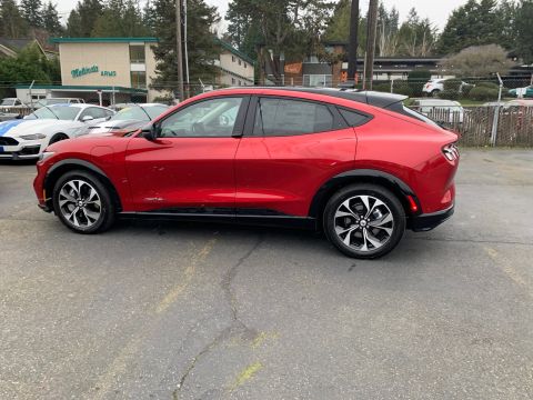 2021 Ford Mustang - A red Ford Mustang Mach-E is parked in a lot, with another vehicle partially visible to its left.