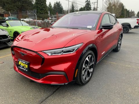 2021 Ford Mustang - A red Ford Mustang Mach-E is parked in a lot with other vehicles visible.