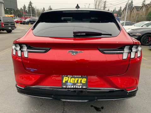 2021 Ford Mustang - The rear of a red Ford Mustang Mach-E is shown, its distinctive taillights and the iconic Mustang horse emblem.