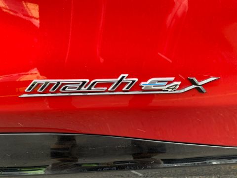 2021 Ford Mustang - Chrome 'mach-E' badge on a red car's body panel.