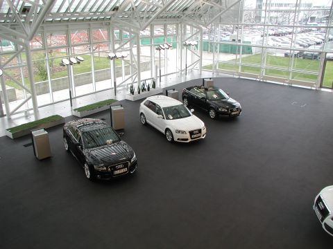 2010 Audi A4 - Multiple Audi vehicles are displayed indoors under a large glass roof structure.