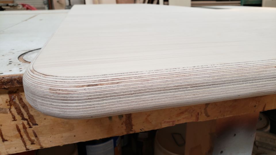 Close-up of a rounded edge on a laminated plywood surface, showing layers of wood