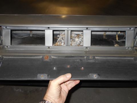 1992 Ford Bronco - A hand is shown removing a panel below the rear vent of a vehicle, revealing insulation and wiring.