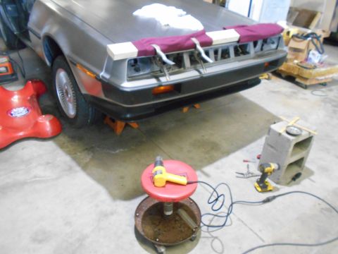 1992 Ford Bronco - A DeLorean DMC-12 is seen on jack stands in a workshop, with its rear end partially disassembled for repairs.