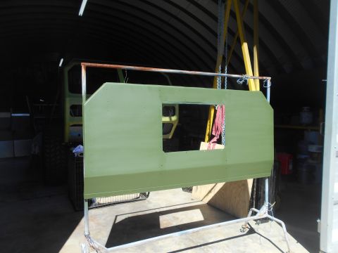 1992 Ford Bronco - A large, green-painted vehicle body panel is suspended for painting inside a workshop.